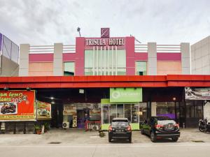 dois carros estacionados num parque de estacionamento em frente a uma loja em Super OYO 3936 Hotel Trisula Makassar em Macáçar