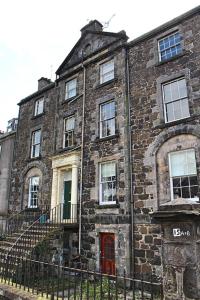un antiguo edificio de ladrillo con una puerta roja en Clan Ross - 3 bed, spacious Georgian home en Stirling