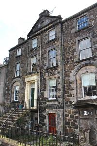 un ancien bâtiment en briques avec une porte rouge dans l'établissement Clan Ross - 3 bed, spacious Georgian home, à Stirling