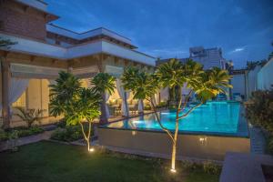 a swimming pool in front of a building with palm trees at The Rohet House in Jodhpur