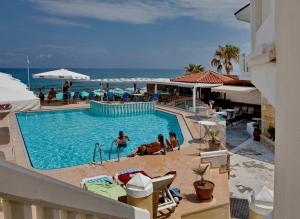 uma piscina num resort com pessoas sentadas em cadeiras em Jo An Beach Hotel em Adelianos Kampos