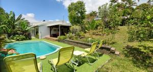 a backyard with a pool and chairs and a house at La Maison Dakoté in Sainte-Clotilde