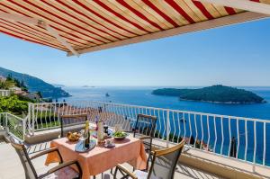balcón con mesa, sillas y vistas al océano en Apartments Cicko en Dubrovnik