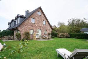 ein großes Backsteinhaus mit einem Hof mit Tisch und Stühlen in der Unterkunft Dat Wiesenhuus in Tinnum