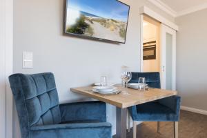 una sala da pranzo con tavolo in legno e sedie blu di Meerblick Appartements a Westerland
