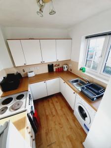 a small kitchen with white cabinets and a wooden floor at 2 Bedroom Rayleigh Apartment in Rayleigh