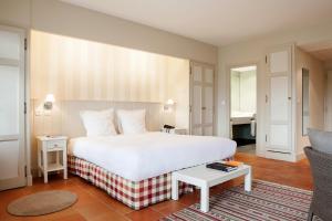a bedroom with a large white bed and a living room at Relais des Vigiers in Monestier
