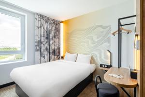 ein Hotelzimmer mit einem großen Bett und einem Schreibtisch in der Unterkunft B&B HOTEL Thionville Centre Gare in Thionville