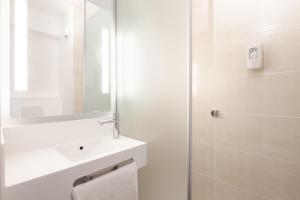 a white bathroom with a sink and a mirror at B&B HOTEL Thionville Centre Gare in Thionville