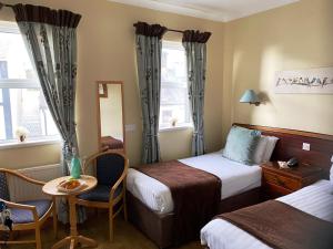 una camera d'albergo con due letti, un tavolo e delle sedie di O'Shea's Hotel a Tramore