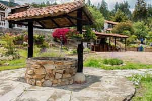 un jardín con un pabellón de madera y una pared de piedra en Villa Patty, en Tibasosa