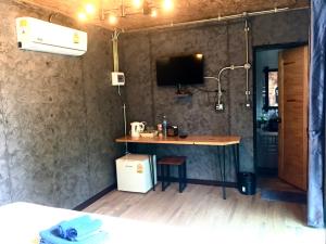a room with a table and a tv on a wall at The Loft Resort Kabin Buri in Kabin Buri