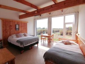 a bedroom with two beds and a table and a window at Hostería de la Patagonia in Chile Chico