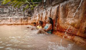 zwei Mädchen sitzen im Wasser an einem Wasserfall in der Unterkunft Recreo Verde Hot Springs & Spa in Marsella