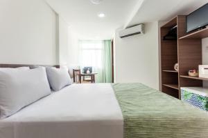 a bedroom with a large white bed and a television at João Pessoa Hplus Beach in João Pessoa