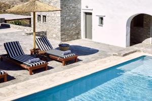 a pair of chairs and an umbrella next to a swimming pool at Acron Villas in Kolympithres