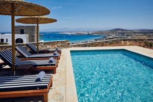 a swimming pool with chairs and umbrellas and the ocean at Acron Villas Paros in Kolympithres