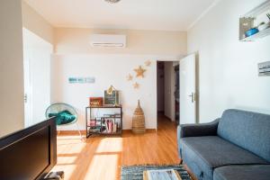 ein Wohnzimmer mit einem Sofa und einem TV in der Unterkunft A Casa da Joana in Costa da Caparica