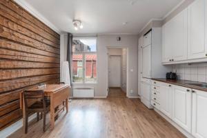 a kitchen with white cabinets and a wooden wall at SELF-SERVICE apt 10 min from bus-&railway station, free bikes! in Vaasa