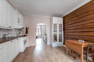 a kitchen with white cabinets and a wooden wall at SELF-SERVICE apt 10 min from bus-&railway station, free bikes! in Vaasa