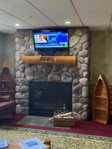a living room with a stone fireplace with a flat screen tv at Hometown Inn Indian River in Indian River