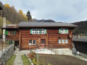 a large wooden house with a stone wall at FeWo aletsch dreams in Fiesch