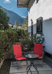 2 sillas rojas y una mesa en el patio en AUGUSTA casa vacanza, en La Thuile