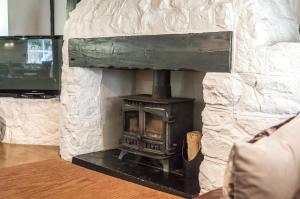 a stone fireplace with a stove in a living room at Barn Conversion - Hot Tub - Penally - Tenby in Penally