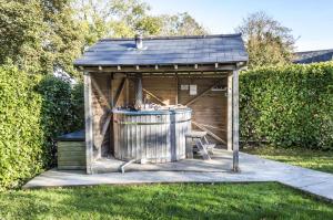 a wooden gazebo with a barrel in a yard at Barn Conversion - Hot Tub - Penally - Tenby in Penally