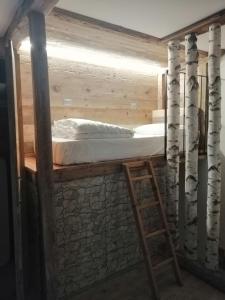 a bed in a tree house with a ladder at FIOCCO DI NEVE in Vezza dʼOglio