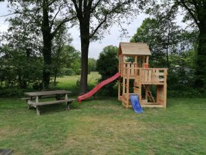 un parque infantil de madera con un tobogán y un banco en Camping 't Bosch, en Zelhem