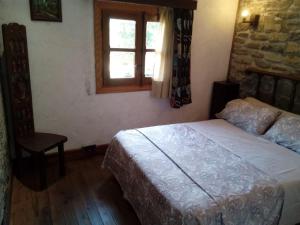 a bedroom with a bed and a window and a chair at Casa del Arco in Aísa