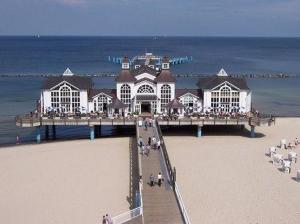 ein Gebäude am Strand mit Leuten, die auf einem Pier spazieren in der Unterkunft "Villa Loni" Ferienwohnung 7 in Ostseebad Sellin