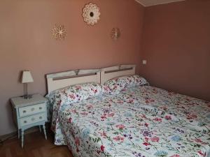 a bedroom with a bed with a floral bedspread and a table at Hospital del Temple Casa Rural in Boquiñeni