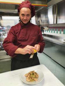 un hombre en una cocina con un plato de comida en Albergo Ristorante Pozzi, en Bellaria-Igea Marina