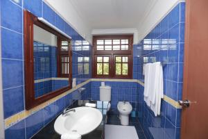 Un baño con azulejos azules, inodoro y lavabo. en Villa 59, en Galle 43 fotos más