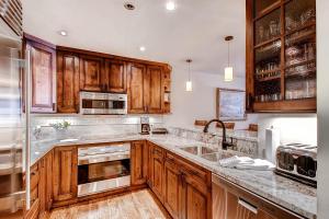 a kitchen with wooden cabinets and stainless steel appliances at Kiva Lodge by East West Hospitality in Beaver Creek