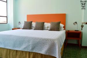 a bedroom with a large bed with an orange headboard at Apartamentos el Prado en Zona 1 - ANAH hotel group in Guatemala