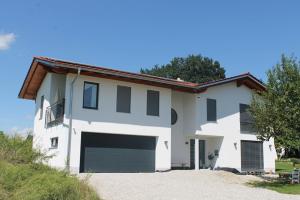 une grande maison blanche avec un grand garage dans l'établissement Ferienwohnung Stocker, à Seeon-Seebruc