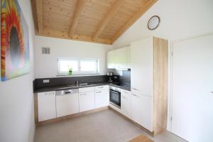 a kitchen with white cabinets and a wooden ceiling at Ferienwohnung Stocker in Seebruck