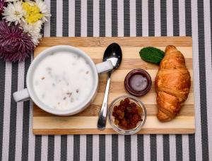 a wooden cutting board with a cup of soup and a croissant at Rooms Hotel in Vinnytsya