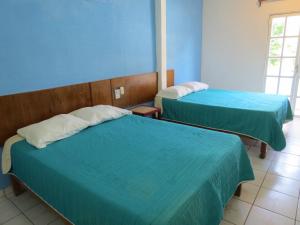 two beds in a room with blue walls at Hotel Albri by Rotamundos in Tecolutla
