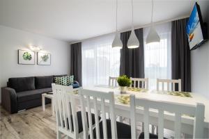 a dining room and living room with a white table and chairs at DOMKI APARTAMENTOWE BARKA in Karwia