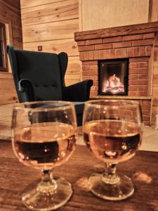 two wine glasses sitting on a table in front of a fireplace at Chata Sosenka in Sygontka