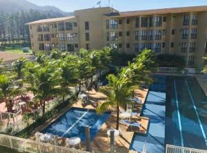 een luchtzicht op een hotel met een zwembad en palmbomen bij Loft Aldeia dos Reis in Mangaratiba