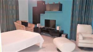 ein Wohnzimmer mit einem Bett, einem TV und Stühlen in der Unterkunft Villa De Rouba in Blue Bay