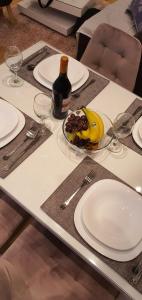 - une table avec des assiettes, un bol de fruits et une bouteille de vin dans l'établissement Apartman Jovana, à Zlatibor