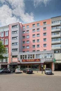 un gran edificio rosa con coches estacionados frente a él en City Hotel Ansbach am KaDeWe en Berlín