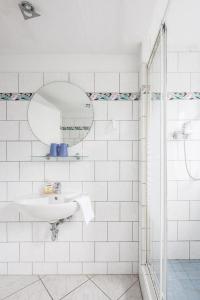 ein weißes Badezimmer mit einem Waschbecken und einem Spiegel in der Unterkunft City Hotel Ansbach am KaDeWe in Berlin