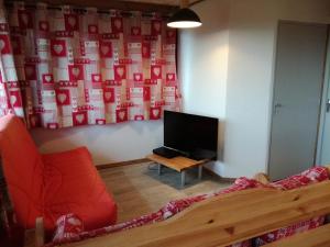 a living room with a red couch and a tv at Gîte Le p'tit Chasseral in Maîche